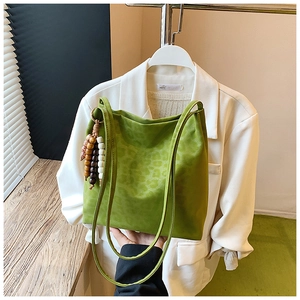 Detail of green leopard print suede tote bag with decorative wooden beaded tassel charm