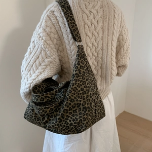 Detailed view of leopard print canvas bag worn over a knit sweater for casual style