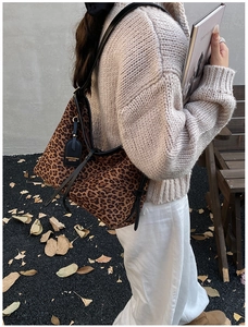 Close-up of leopard print tote bag with black leather trim and decorative tag detail