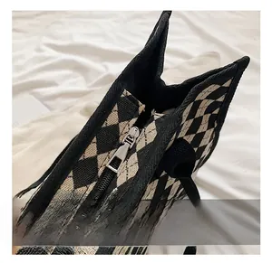 Detail view showing smooth metal zipper closure and woven handles of checkered tote bag