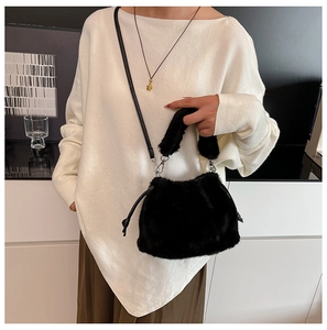 Black fluffy plush bucket bag with chain strap and soft faux fur handle in luxury setting
