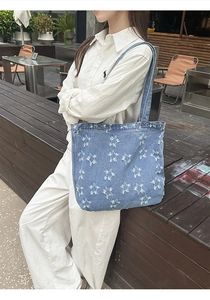 Detail of light blue denim tote bag with frayed star patterns in a retro street style