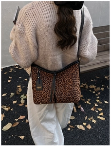Detail of leopard print tote bag with black leather straps and golden brand tag