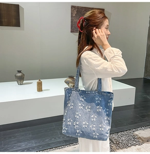 Detail of blue denim tote bag with frayed star patterns and spacious shopper interior