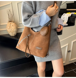 Brown suede hobo tote bag with zipper details and matching round coin purse on a model