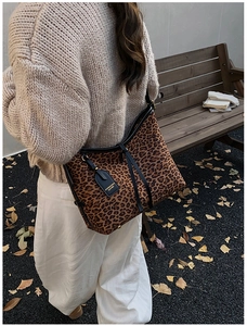 Close-up of leopard print tote bag with black leather trim shown in an autumn setting
