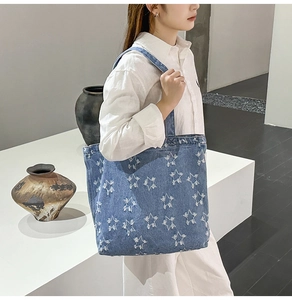 Detailed view of blue denim tote bag with fuzzy white star patterns worn by a model