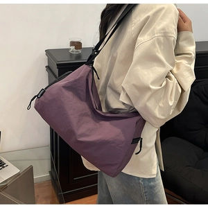 Close-up of deep purple crinkled nylon fabric and Fashion tag on large crossbody bag