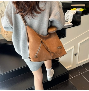 Detail of a brown matte faux leather hobo bag with a round coin purse and zipper pocket
