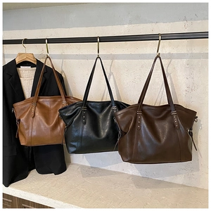 Détail de grands sacs cabas marron et noir avec rivets en étoile suspendus à une barre métal