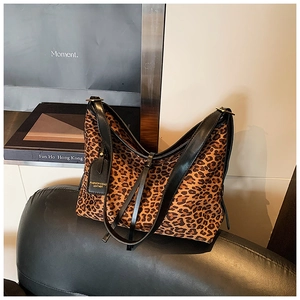 Macro detail of leopard print tote bag featuring black leather strap and designer tag