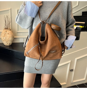 Detail of caramel suede hobo bag featuring side metal zipper and small detachable round pouch
