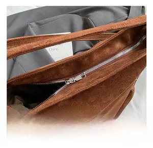 Gros plan sur un sac cabas en daim marron avec fermeture éclair en métal argenté et couture
