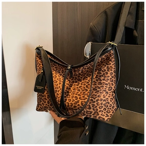 Macro detail of leopard print tote bag featuring black leather strap and fashion tag