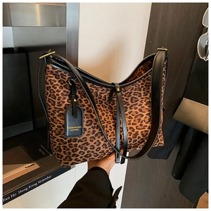 Detail of leopard print tote bag featuring black leather straps and hanging tag accessory