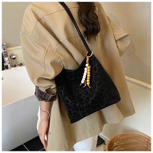 Detail of vintage black leopard print bucket bag featuring bohemian wooden bead tassel