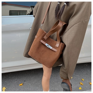 Detailed view of brown suede bucket bag with silver clasp in a casual autumn street style