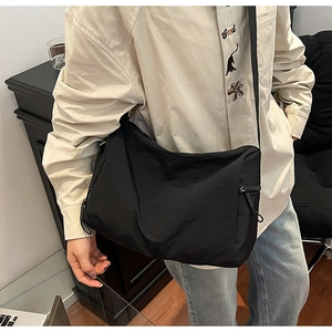 Detail view of large black nylon messenger bag with zipper closure and wide strap