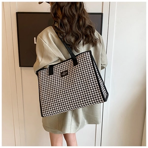 Detail of checkered tote bag with woven shoulder strap and chic branded label