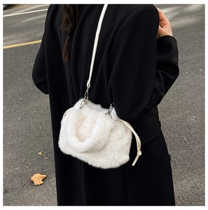 Gros plan d'un sac bandoulière blanc en peluche avec chaîne porté sur un manteau noir