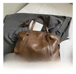 Détail du sac cabas en cuir marron texturé avec poignées et bandoulière réglable