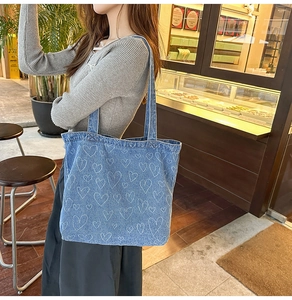 Detail of light blue denim tote bag with white heart prints in a cafe setting
