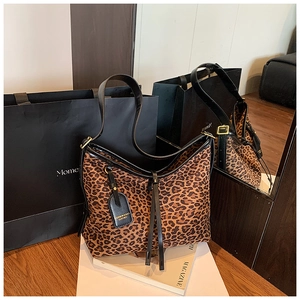 Close-up of leopard print tote bag featuring black leather straps and hanging tag detail