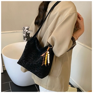 Detail of black leopard print suede shoulder bag featuring colorful wooden bead tassel