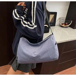 Detail of light purple nylon crossbody bag with fashion label and black strap strap
