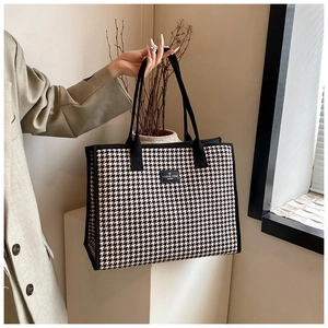 Detail of checkered tote bag featuring a leather patch and durable woven handles