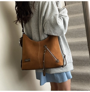 Close-up of brown frosted leather tote bag showing diagonal zipper and soft texture