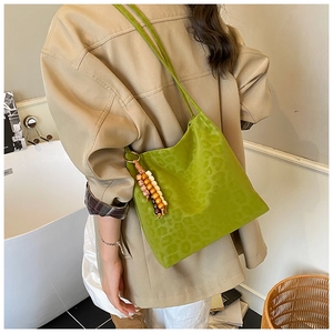 Detail of lime green leopard print shoulder bag with decorative wooden beaded tassel