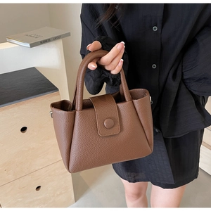 Détail d'un sac seau marron foncé avec texture grainée de luxe et poignée en cuir élégante