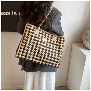 Rear view of model wearing a large checkered canvas tote bag with beige straps