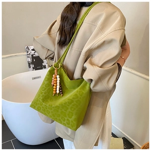 Close-up of green leopard print bucket bag with vintage beaded charm and suede texture