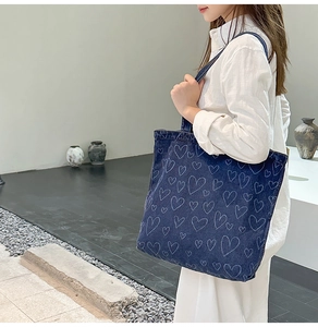Detail of large denim tote bag featuring blue heart patterns and spacious storage design