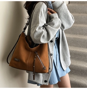 Detail of caramel brown suede tote bag with zipper pocket and dark brown leather strap