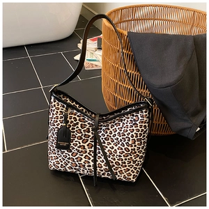 Detail shot of leopard print shoulder bag with black leather strap and metal logo tag