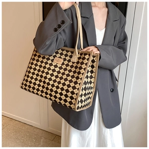 Detail of checkered canvas tote bag with leather label showing texture and handle