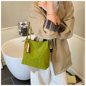 Detail of green leopard print bucket bag with colorful beaded charm and soft texture