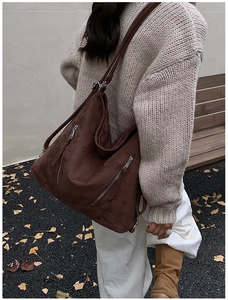 Détail d'un grand sac à bandoulière en daim marron avec fermeture éclair latérale
