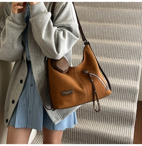 Detail of caramel brown suede tote bag with side zipper and round coin purse charm