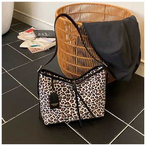 Detail of leopard print tote bag with black shoulder strap and leather tassel accent