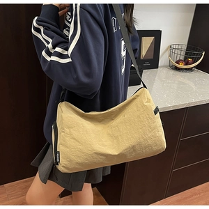Close-up of beige crossbody bag with textured fabric and fashion label detail