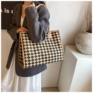 Detailed view of checkered canvas tote bag with reinforced handles on a model