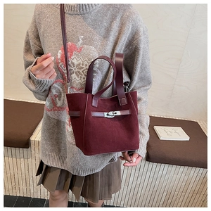 Close-up of burgundy suede bucket bag with silver metal twist lock and dual straps