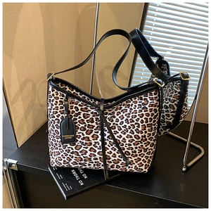 Detailed view of leopard print tote bag with black leather straps and adjustable buckle
