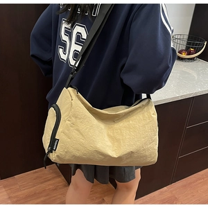 Detail of light beige large-capacity crossbody bag with black zippers and fashion label