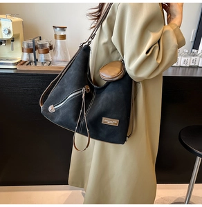 Detail of black tote bag with brown leather trim and a small round coin purse attachment