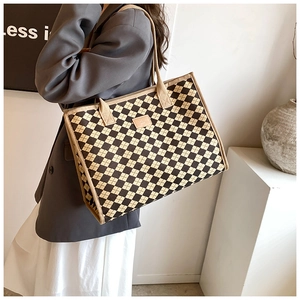 Detail of checkered canvas tote bag showing thick texture and shoulder strap on model